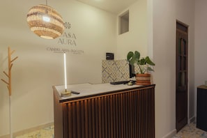 Una recepción de diseño moderno, una lámpara colgante, una planta en maceta y una pared con un diseño geométrico.