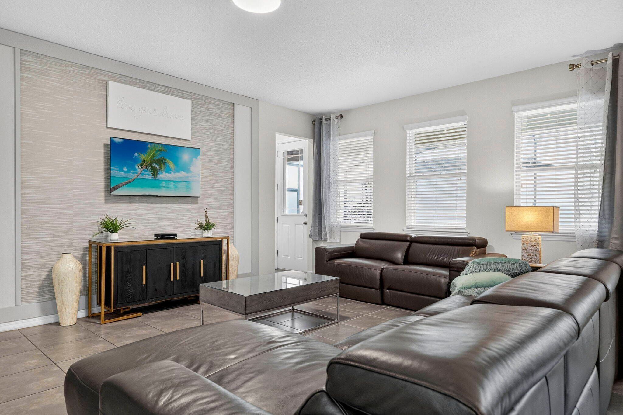 A modern living room with a leather sofa, a glass coffee table, and a cabinet with decorative items.