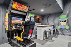 Ein Spielsalon mit Renn- und Actionspielen, einer Bar und einer Wandmalerei mit Comicfiguren.