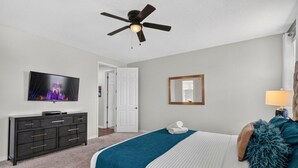 A bedroom with a bed, a dresser, a television, a ceiling fan, a door, and a mirror. - House 7Q With Pool, Spa and Game Room (Kissimmee)