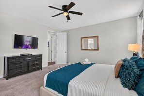 A bedroom with a bed, a dresser, a television, a ceiling fan, a door, and a mirror. - House 7Q With Pool, Spa and Game Room (Kissimmee)