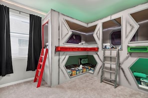 Ein Zimmer mit einem Etagenbett, einer Stehleiter und einer Inneneinrichtung im Stil von Star Wars.