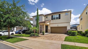 A two-story residential building with a garage, a covered entryway, and a well-maintained lawn. - House 7Q With Pool, Spa and Game Room (Kissimmee)