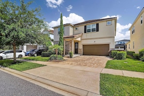 A two-story residential building with a garage, a covered entryway, and a well-maintained lawn. - House 7Q With Pool, Spa and Game Room (Kissimmee)