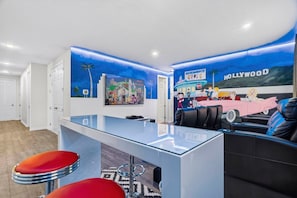 A modern interior with a bar area, seating, and a mural depicting a Hollywood theme. - House 7Q With Pool, Spa and Game Room (Kissimmee)