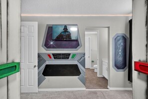 A room with a Star Wars-themed wall, a television mounted above a control panel, and a door with a green handle. - House 7Q With Pool, Spa and Game Room (Kissimmee)