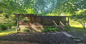 A wooden cabin with a porch and a staircase, surrounded by greenery. - Located across the street from LaPrade's Marina on Lake Burton, and just 15 miles from the historic Lake Rabun Hotel and downtown Clayton, the Cona LaPrade Cabin is perfectly situated to enjoy the best of North Georgia's mountains and lakes.  <br><br (Clarkesville)