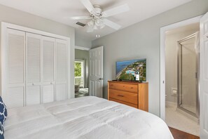 A bedroom with a bed, a dresser, a ceiling fan, and a door leading to a balcony. - Breezy Bliss located near Coast Guard Beach Entrance, sleeps 9 (St. Simons Island)