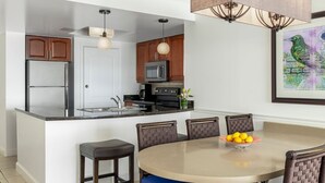 A modern kitchen with a central island, wooden cabinets, stainless steel appliances, and a dining area with a round table and chairs. - ST. THOMAS vacation resort in  the tropical U.S. Virgin Islands. (St Thomas)