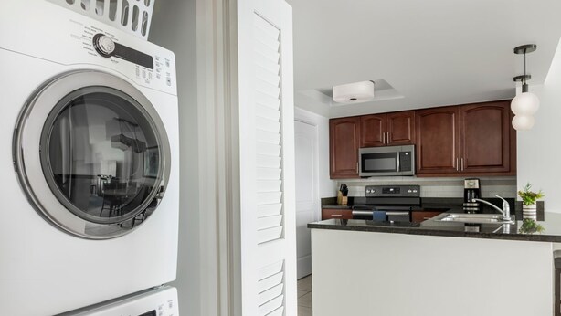 A compact kitchen with a built-in washer and dryer, wooden cabinets, and a modern microwave. - ST. THOMAS vacation resort in  the tropical U.S. Virgin Islands. (St Thomas)