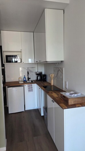 A compact kitchen with white cabinets, a microwave, a coffee maker, and a dishwasher. - A Cozy One-Bedroom Apartment in a Charming, Authentic Village (Saint-Fort-sur-Gironde)