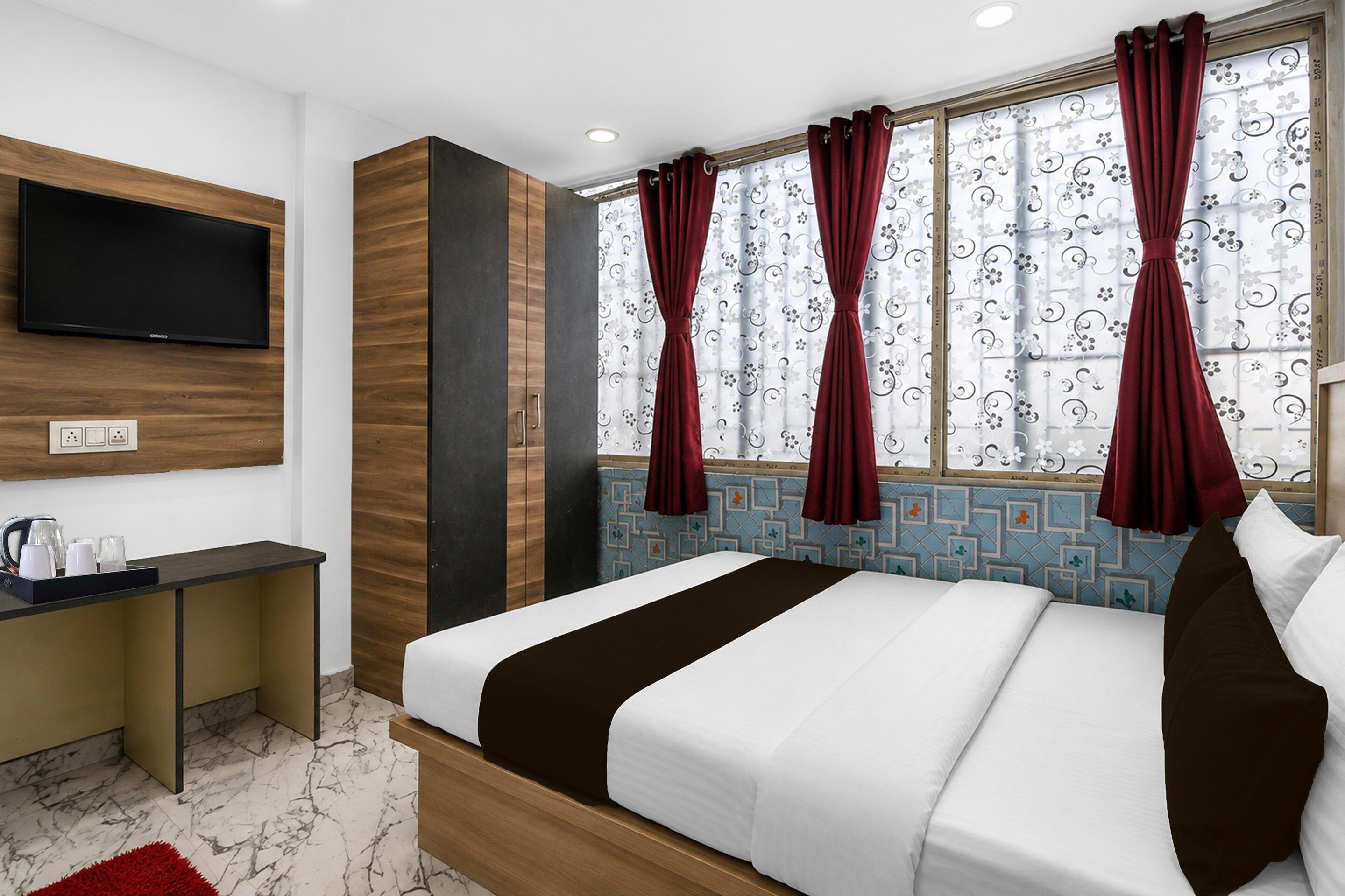 Ein Hotelzimmer mit einem Bett, einem Schreibtisch, einem Fernseher und einem fenster mit Vorhängen.