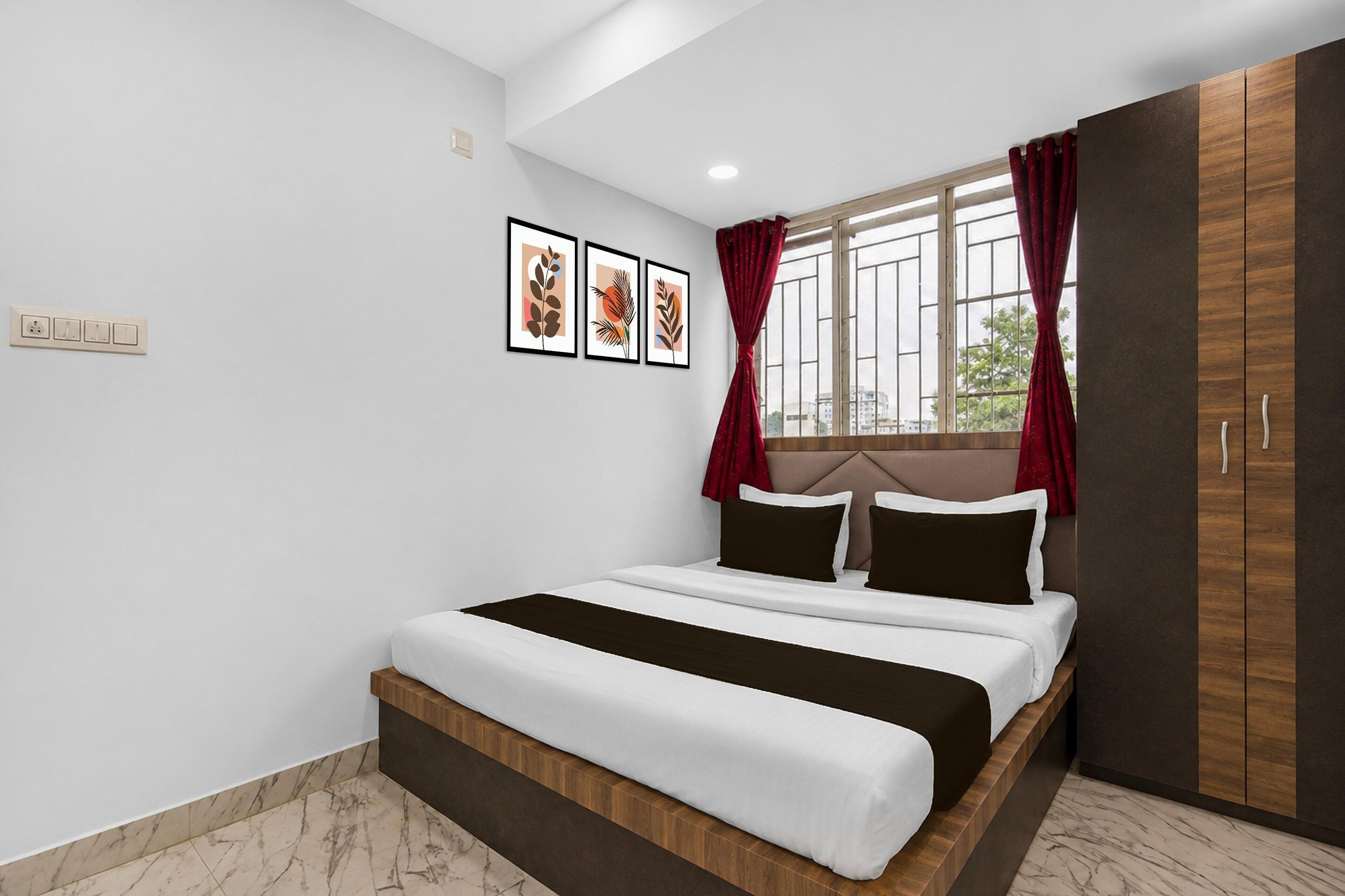 Een slaapkamer met een bed, een kledingkast, een raam met gordijnen en een wandcontactdoos.