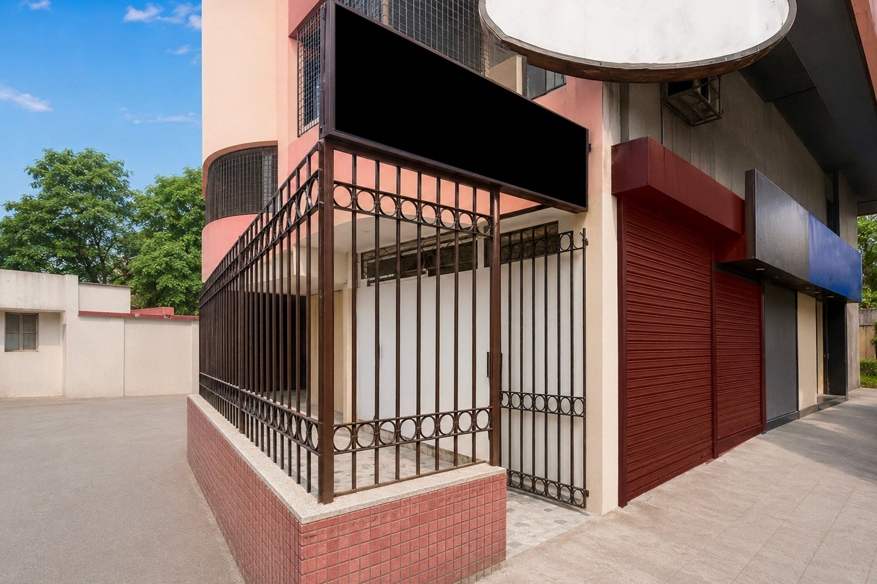 Un bâtiment doté d’une entrée fermée par un portail, d’une porte de garage rouge et d’une grande fenêtre circulaire.