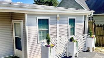 A single-story building with a garage door, two windows, and a small porch area with planters.