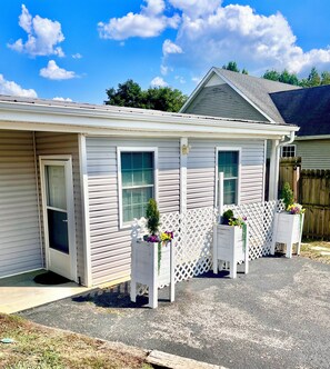 A single-story building with a garage door, two windows, and a small porch area with planters.