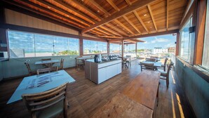 An open-plan restaurant with a high ceiling and large windows overlooking a cityscape. - POUSADA VIVA MARAGOGI (Maragogi)
