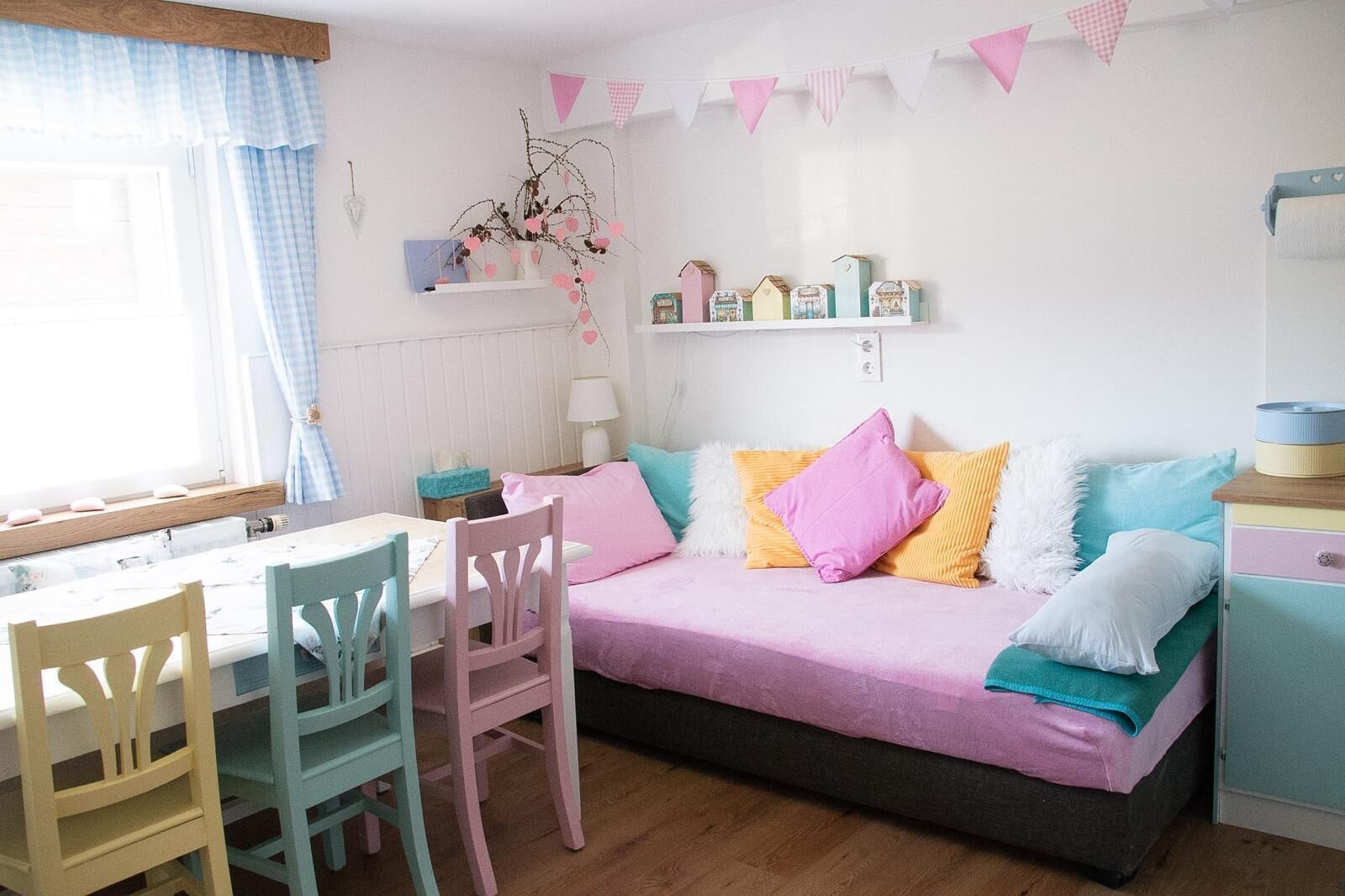 Een gezellige kamer met een bed, een tafel, stoelen en een plank met decoratieve objecten.