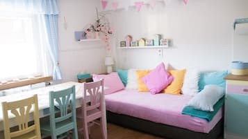 Een gezellige kamer met een bed, een tafel, stoelen en een plank met decoratieve objecten.