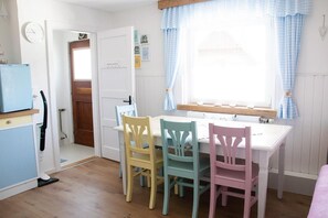 A small dining area with a white table and four chairs, a clock on the wall, and a window with curtains. - Escape the gray routine—and dive into colorful mountain bliss! At just under 1,100 meters above sea level! (Knappenberg)