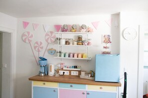A kitchen with a wooden countertop, colorful cabinets, a blue refrigerator, and various kitchen items on shelves. - Escape the gray routine—and dive into colorful mountain bliss! At just under 1,100 meters above sea level! (Knappenberg)
