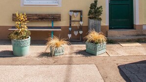 Una casa de fusta amb façana groga, una porta verda i una finestra amb decoracions de cor.