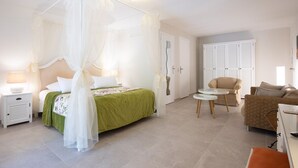 Un dormitorio con una cama con dosel, una mesita de noche con lámpara, una colcha verde, una silla, un sofá y un armario.
