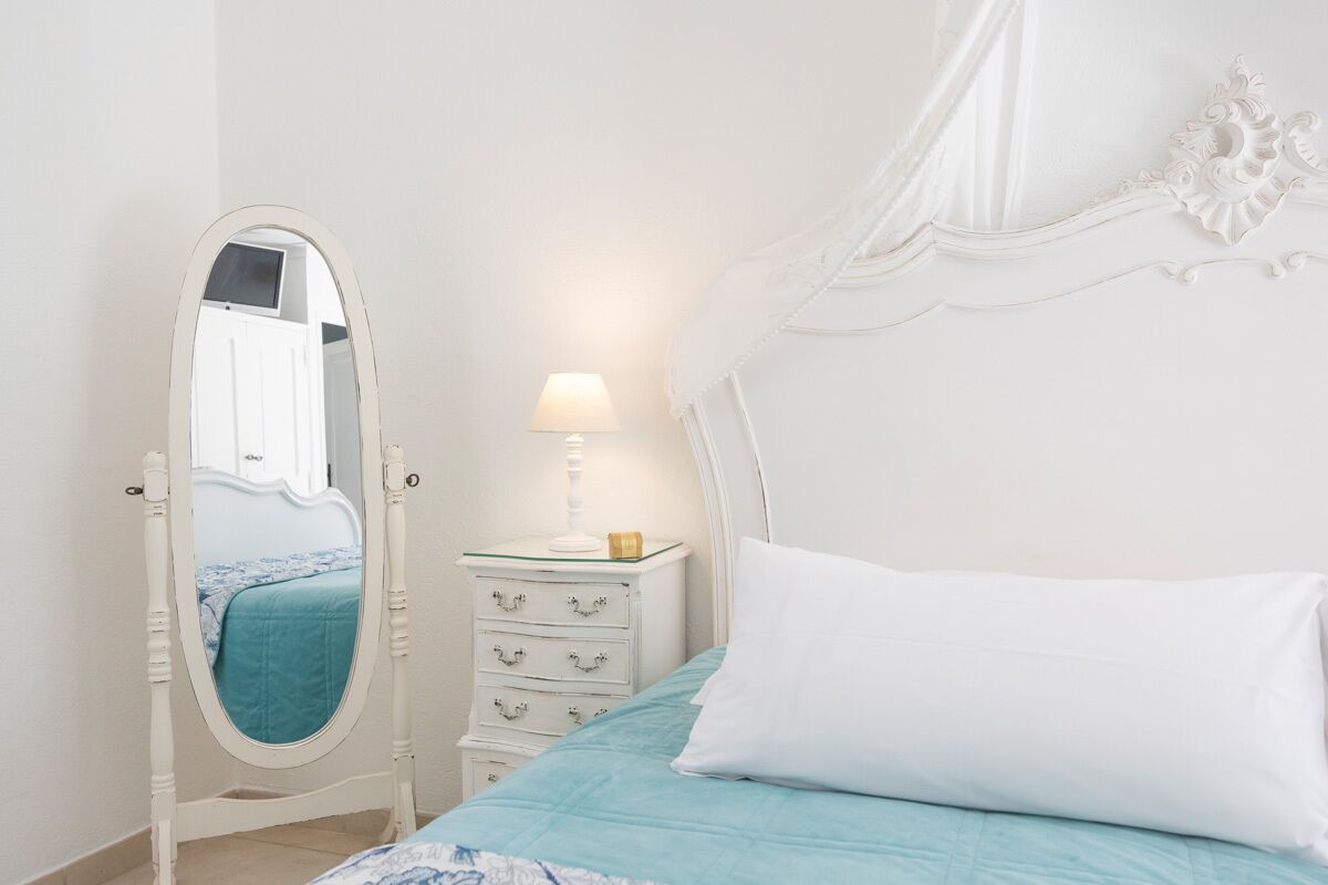 Une chambre à coucher avec un lit, une table de chevet avec une lampe, une commode et un miroir.