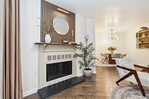 A modern living room with a fireplace, a dining area with a round table, and a seating arrangement.
