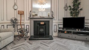 Een woonkamer met een open haard, een televisie en een bank.