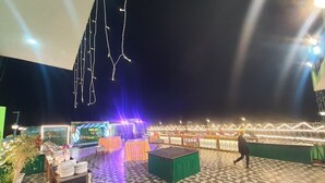 An outdoor event space with tables and chairs, a stage, and decorative lighting.