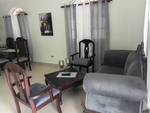A living room with a dining table, two chairs, a sofa, and a decorative lamp. - Delightful 2-bedroom house with AC in Puerto Plata (Puerto Plata)