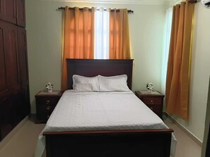 A bedroom with a single bed, two nightstands, and a wooden wardrobe. - Delightful 2-bedroom house with AC in Puerto Plata (Puerto Plata)