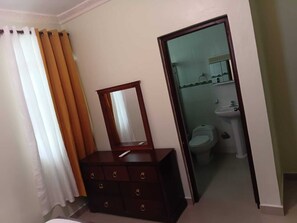 A room with a wooden dresser, a mirror, and a bathroom visible through an open door. - Delightful 2-bedroom house with AC in Puerto Plata (Puerto Plata)