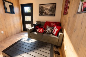 Quarto com sofá cinzento, mesa de centro preta e quadro emoldurado na parede.
