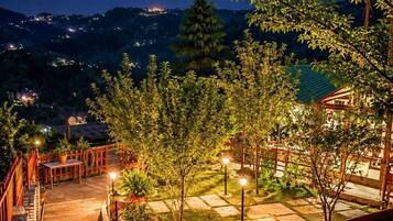 A nighttime outdoor area with a pathway leading to a building, surrounded by trees and illuminated by street lamps.