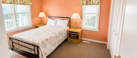 A bedroom with a bed, two nightstands, two lamps, a window with blinds, and a door.