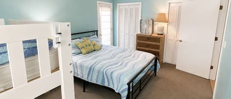 Un dormitorio con cama, cómoda, mesita de noche y puerta.