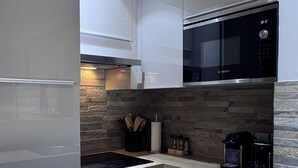 Cozinha moderna com armários brancos, micro-ondas Bosch e forno embutido.