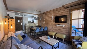 Ein modernes Wohnzimmer mit einer Couch, einem Couchtisch und einem an einer Holzwand montierten Fernseher.