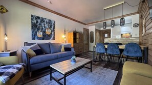 Ein modernes Wohnzimmer mit Sofa, Couchtisch und Essbereich mit Stühlen.
