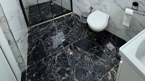 A bathroom with a shower, toilet, and marble flooring. - Öz tralles otel (Aydın)