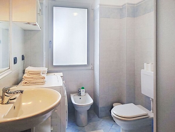 Ein Badezimmer mit Waschbecken, Bidet, Toilette und einem Fenster.