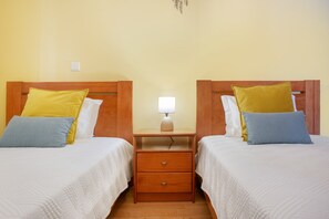 A double room with two beds, each with a wooden headboard, a bedside table, and a lamp. - Casa D'Avó Apartment with Sea View and Private Terrace (Santa Cruz)