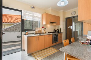 Eine moderne Küche mit Holzschränken, einem Gasherd und einem Essbereich mit Stühlen.