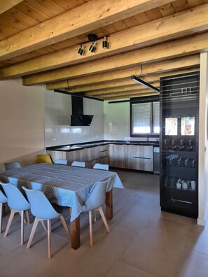 Una cocina moderna con comedor, vigas de madera en el techo y electrodomésticos integrados.
