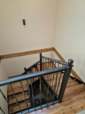 A wooden staircase with a metal handrail and balusters.