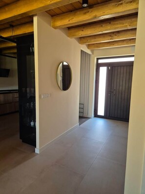 A spacious room with a high ceiling, a round mirror on the wall, and a door leading to another area.