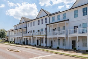 A row of townhouses with front porches and a brick-paved street. - The Dolly (Oxford)
