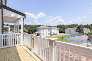 A residential area with a wooden deck, white railings, and a tennis court. - The Dolly (Oxford)